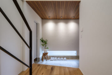 千葉県の注文住宅玄関スペース。間接照明とウッド天井が高級感を演出。収納も充実した設計。